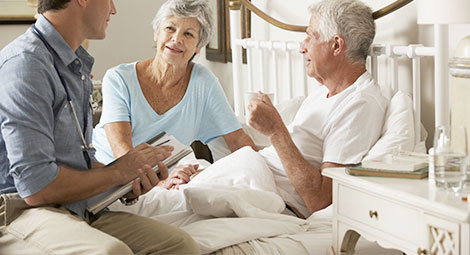 An older couple being visited by a doctor at home 